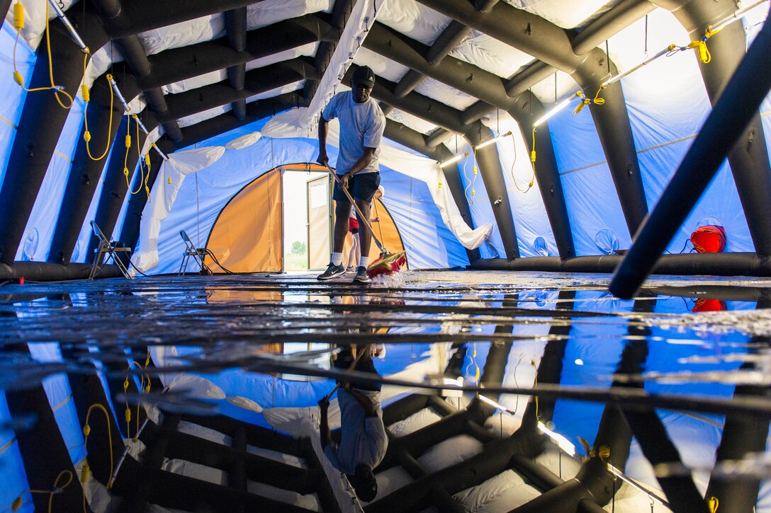 An airman uses a mop on a wet floor.