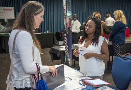 Janice Taylor, a representative from the Defense Finance & Accounting Service speaks with a potential candidate Sept. 19, 2018, during the Joint Base San Antonio-Fort Sam Houston, Texas,  Department of Defense Hiring Heroes Career Fair. Army Emergency Relief recently announced a new program that would reimburse spouses up to $2,500 for relicensing expenses, making it easier for them to continue their careers when they move to another state.