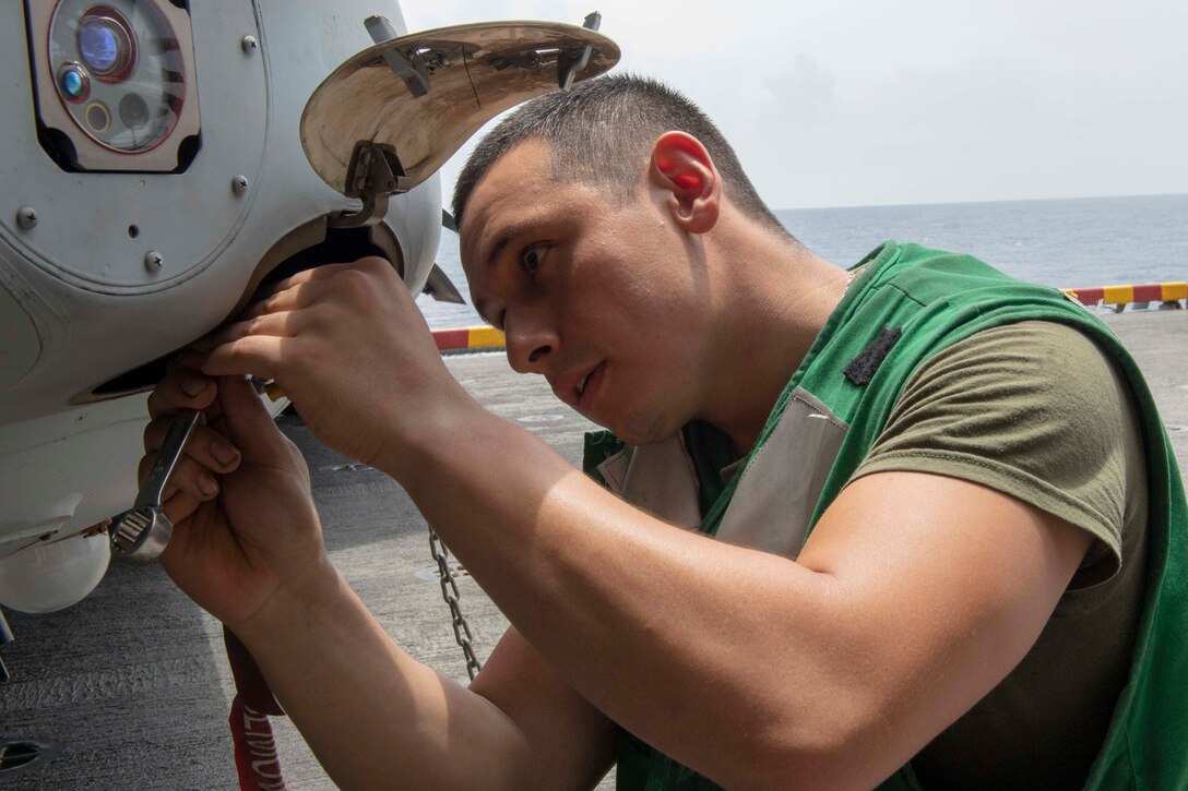A Marine uses a wrench to fix a part on an aircraft.