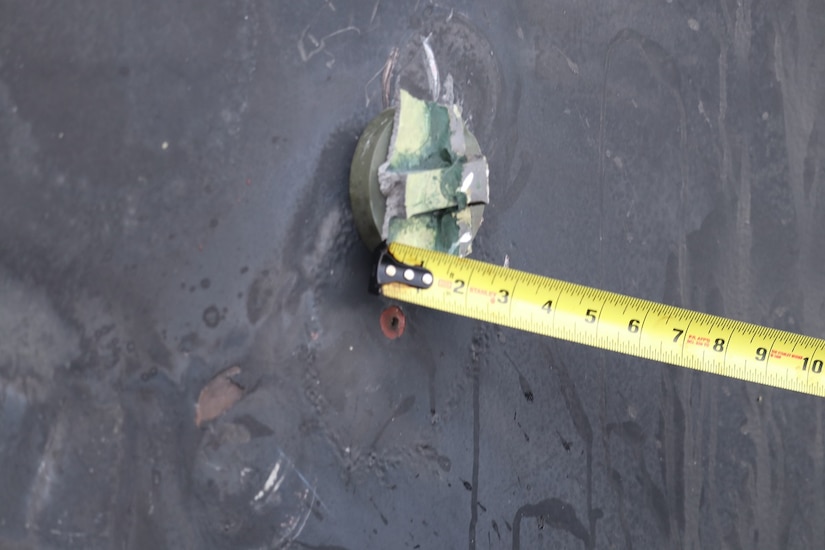 Tape measure marks metal stuck to side of oil tanker.