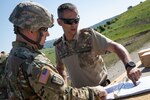An engineer from the West Virginia Army National Guard (WVARNG) looks over plans with a Romania soldier June 19, 2019, at the Cincu Training Area in Cincu, Romania. West Virginia Army National Guard engineers are participating in Resolute Castle 19, a multi-national joint exercise that conducts troop construction engineer projects and reinforces regional assurance and deterrence while strengthening partnership capacity with NATO allies. (U.S. Army National Guard photo by Sgt. Zoe Morris)