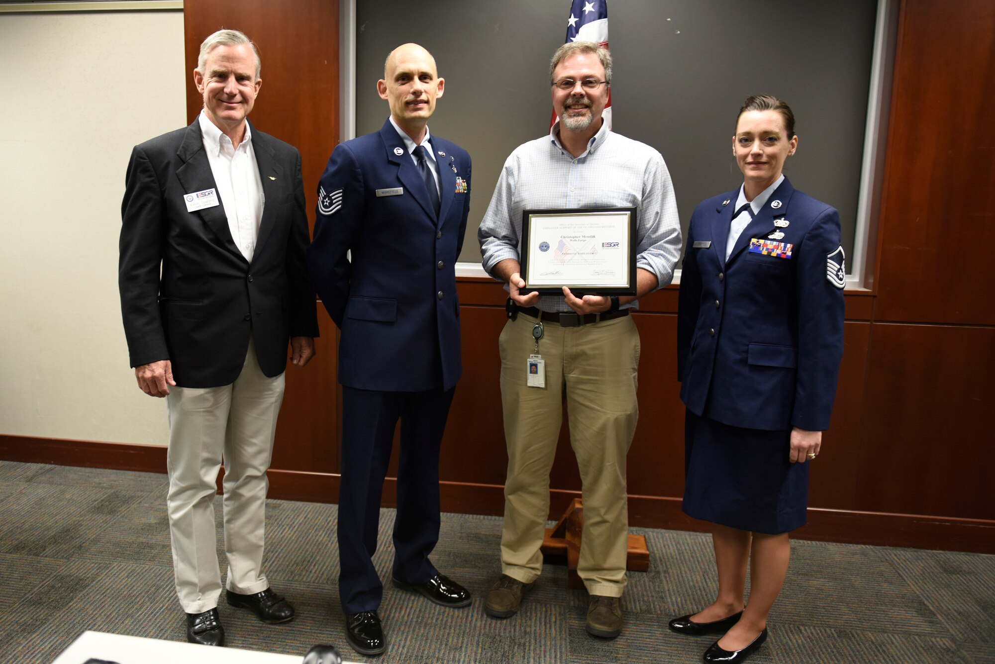 From left to right Mr. Kevin Spalding Area Chair with the North Carolina ESGR, U.S. Air Force Tech. Sgt. Stacey Wakefield of the 156th Aeromedical Evacuation Squadron, Mr. Chris Mendlik Wells Fargo Information Security Manager, and Master Sgt. Sara Evans with the 131st Bomb Wing pose for a photo after presenting Mr. Mendlik the ESGR Patriotic Employer Award at the Wells Fargo Charlotte Customer Information Center, NC, June 14, 2019. The Patriotic Employer Award is the first level that an employer can be nominated for, and reflects the efforts made to support citizen warriors through a wide-range of measures including flexible schedules, time off prior to and after deployment, caring for families, and granting leaves of absence if needed.