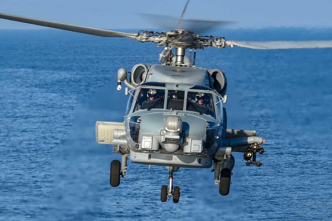 A helicopter flies above water as it heads toward the camera.