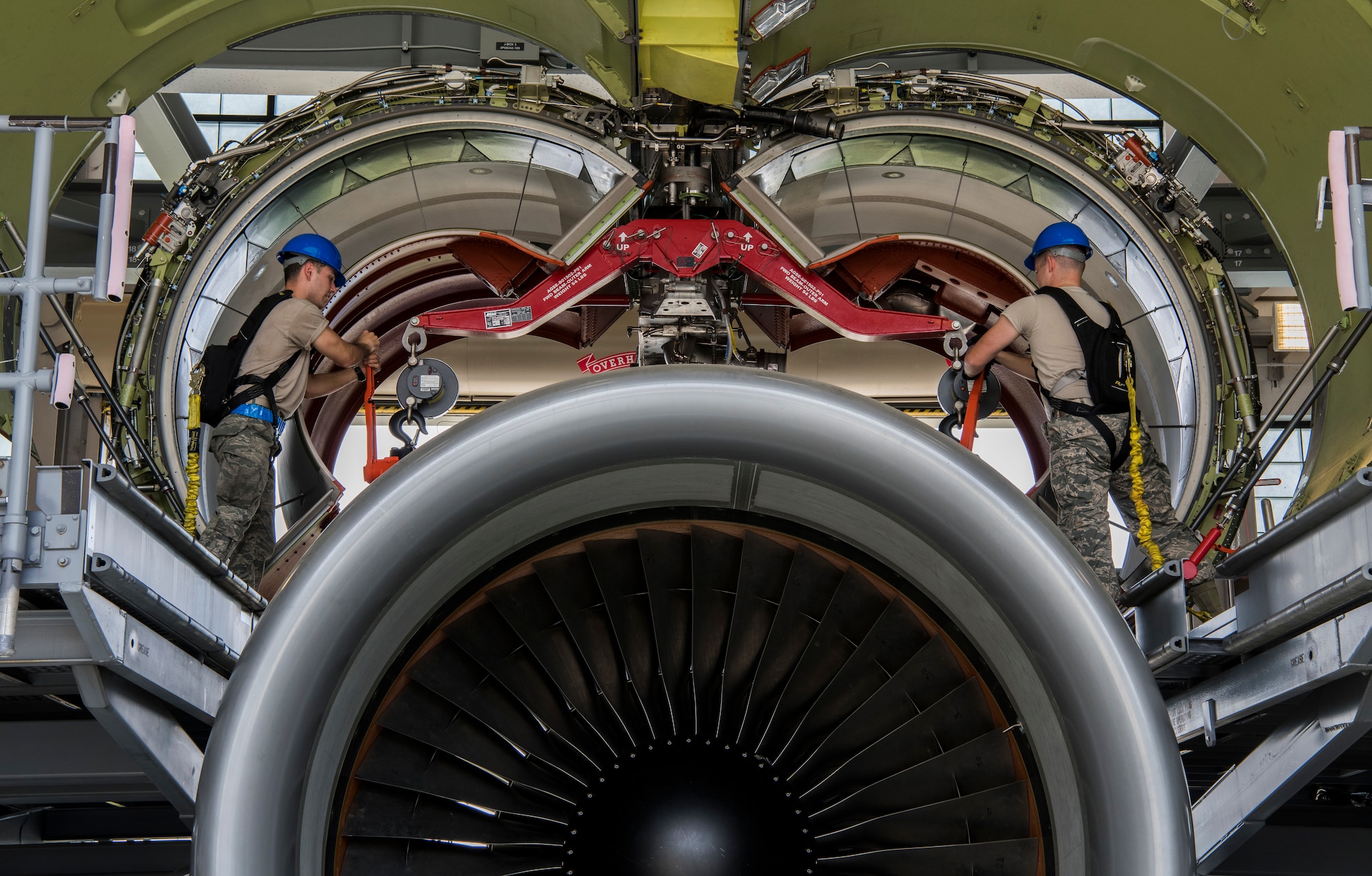 Senior Airman Chad Helminiak, 60th Aircraft Maintenance Squadron aerospace propulsion journeyman, left, and Staff. Sgt. Randolph Quarteroni 725th Air Mobility Squadron aerospace propulsion craftsman, right, lower a C-5M Super Galaxy engine June 6, 2019, Dover Air Base, Del. The engine needs to be balanced from the front, back and from each side while it is being lowered and raised. In order to accomplish this, each Airman must be able to communicate effectively as a team all while cranking and checking the scales attached to the engine. (U.S. Air Force photo by Senior Airman Christopher Quail)