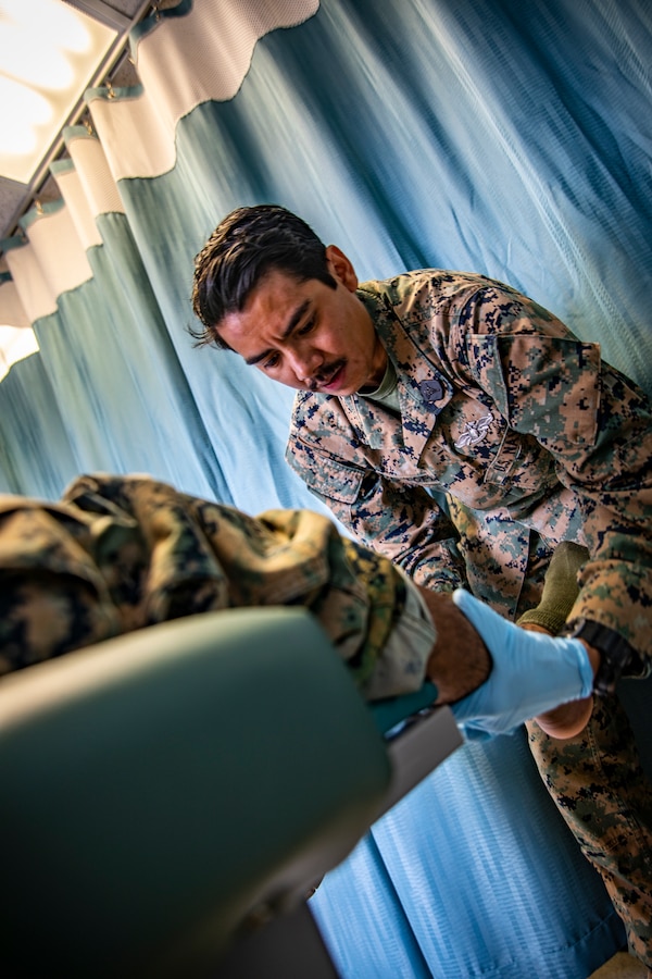 U.S. Navy Petty Officer 3rd Class John Lopes, right, a corpsman with Marine Wing Support Squadron 473, Marine Aircraft Group 41, 4th Marine Aircraft Wing, inspects a patient’s ankle at Canadian Forces Base Cold Lake, Canada, June 14, 2019, in support of Sentinel Edge 19. U.S. Navy Corpsman play a significant role in Reserve Marines’ annual trainings to ensure the Reservist are healthy and able to continue their mission. (U.S. Marine Corps photo by Sgt. Andy O. Martinez)