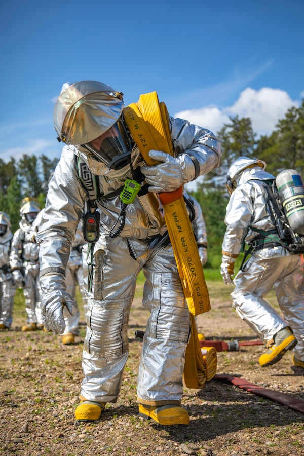 A U.S. Marine aircraft rescue and firefighting specialist with Marine Wing Support Squadron 471, Marine Aircraft Group 41, 4th Marine Aircraft Wing, carries a fire hose during combined firefighting training at Canadian Forces Base Cold Lake, Canada, June 16, 2019, in support of Sentinel Edge 19. The Marine Reserve plays a critical component to the Marine Corps’ Total Force, and training such as SE19 helps ensure Reserve units combat effectiveness and proficiency for world-wide deployment. (U.S. Marine Corps photo by Sgt. Andy O. Martinez)