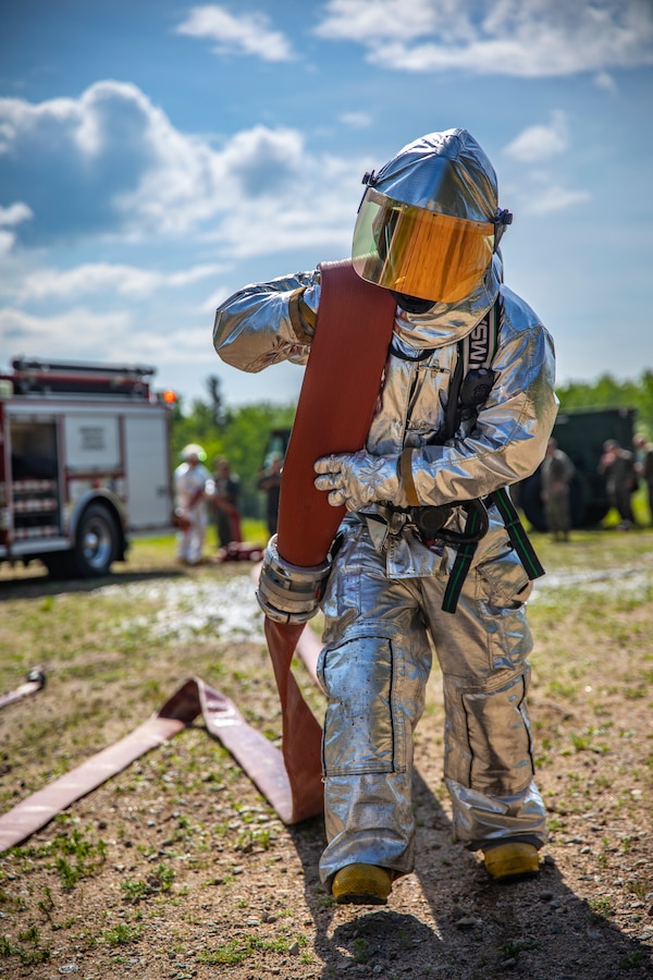 A U.S. Marine aircraft rescue and firefighting specialist with Marine Wing Support Squadron 471, Marine Aircraft Group 41, 4th Marine Aircraft Wing, drags a fire hose during combined firefighting training at Canadian Forces Base Cold Lake, Canada, June 16, 2019, in support of Sentinel Edge 19. The Marine Reserve plays a critical component to the Marine Corps’ Total Force, and training such as SE19 helps ensure Reserve units combat effectiveness and proficiency for world-wide deployment. (U.S. Marine Corps photo by Sgt. Andy O. Martinez)