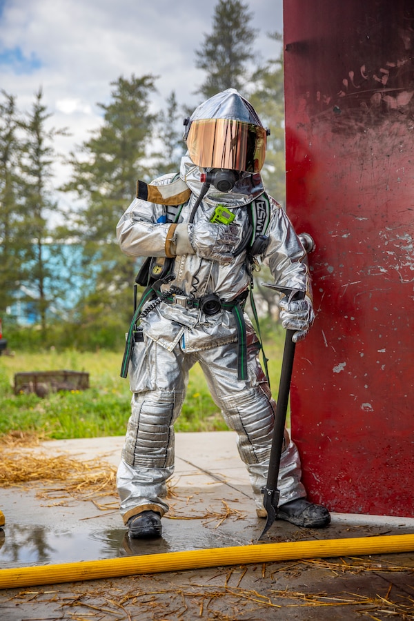 A U.S. Marine aircraft rescue and firefighting specialist with Marine Wing Support Squadron 471, Marine Aircraft Group 41, 4th Marine Aircraft Wing, holds a door open while Marines extinguish a fire in a burning room during combined firefighting training at Canadian Forces Base Cold Lake, Canada, June 16, 2019, in support of Sentinel Edge 19. The Marine Reserve plays a critical component to the Marine Corps’ Total Force, and training such as SE19 helps ensure Reserve units combat effectiveness and proficiency for world-wide deployment. (U.S. Marine Corps photo by Sgt. Andy O. Martinez)