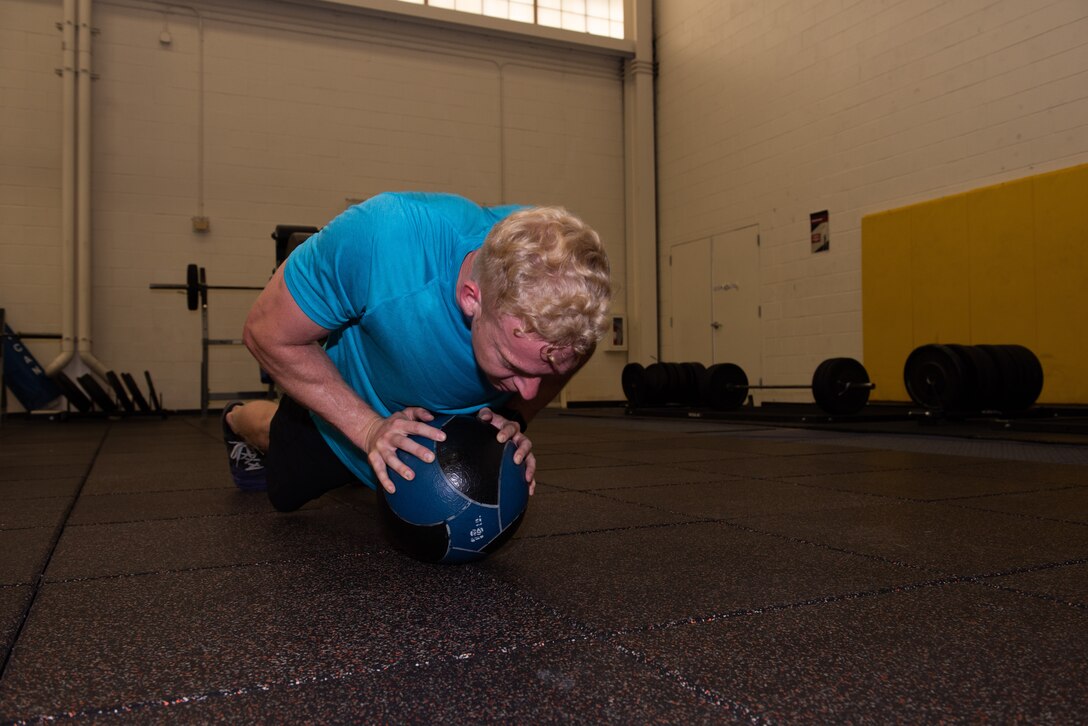 U.S. Air Force Capt. Christopher Williston, a 21st Airlift Squadron C-17 Globemaster III pilot from Baton Rouge, Louisiana, performs push-ups on an 18-pound medicine ball during a workout June 13, 2019, at Travis Air Force Base, California. Williston is training to compete in the Alpha Warrior Western Regional Competition June 21 at Hill AFB, Utah. (U.S. Air Force photo by Tech. Sgt. James Hodgman)