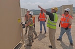 Property Disposal Specialist Parry Miller guides the construction of a mobile command and control shelter at Camp Bondsteel in Kosovo. Miller will serve as the disposal site lead for two weeks as a DLA Disposition Services team torches, shreds and removes broken down equipment the U.S. Army has accumulated during its peacekeeping mission there.