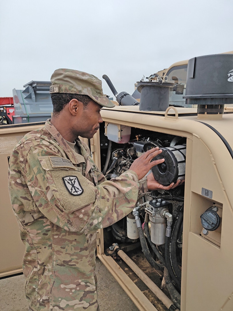 U.S. Army Sgt. Brian Mitchell, a member of DLA's Disposition Services Unit 1, out of Joint Base Lewis-McChord, examines the engine on material handling equipment his team will use at its mobile site in Kosovo in June.