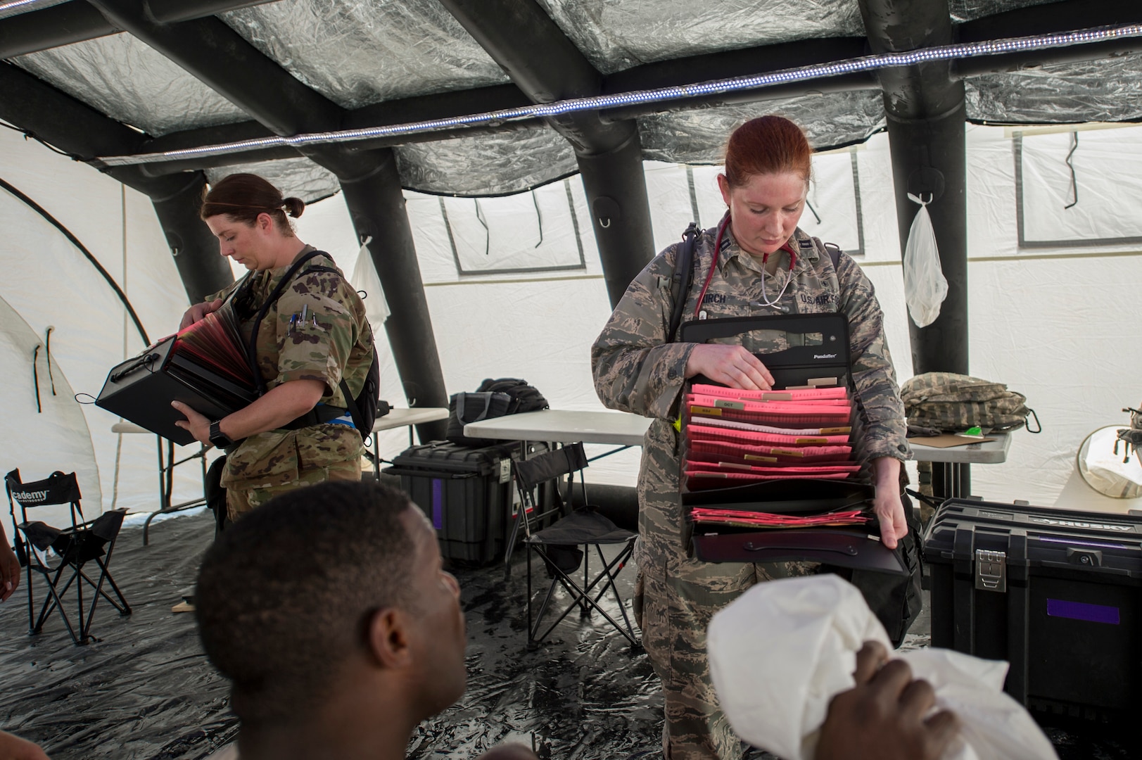 U.S. Air Force Master Sgt. Nichole Stafford (L), the nursing services superintendent and Capt. Shyla Kirch (R), a nurse, both with the 116th Medical Group, Detachment 1, give participants paperwork during rest cycles at FEMA exercise Shaken Fury 2019 on June 5 in Millington, Tenn. Forty-four medical and communications personnel with the 116th Air Control Wing, Georgia Air National Guard, served on the CBRNE Enhanced Response Force working alongside more than 200 Georgia National Guard soldiers, testing the synergy necessary to support the community during natural disasters like the simulated earthquake in the exercise. (U.S. Air National Guard photo by Tech. Sgt. Nancy GoldbergerRELEASED)