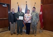 Tech Sgt. Sean Price, a boom operator with the 151st Air Refueling Wing, Utah Air National Guard, stands with his wife Kelly, Utah Governor Gary Herbert and The Adjutant General of the Utah National Guard, Major General Jefferson Burton, April 22, 2019 at Roland R. Wright Air National Guard Base, Salt Lake City, Utah. Price was presented with the Utah Cross award for providing lifesaving first aid to an injured driver. (U.S. Air National Guard photo by Tech. Sgt. John Winn)