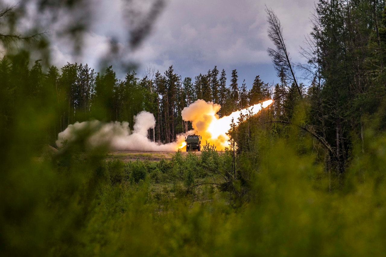 A rocket fired from behind a military vehicle that is surrounded by trees.