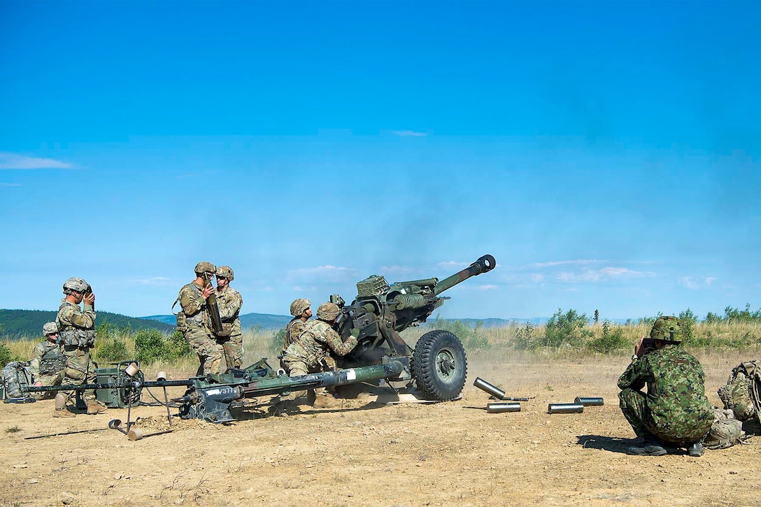 Soldiers fire a large military gun.