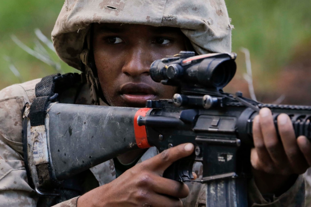 A Marine recruit holds a gun to his shoulder.