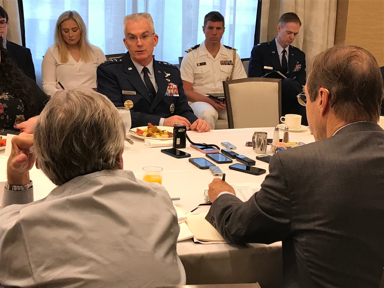 General speaks to a table full of reporters.