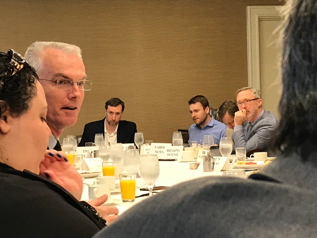 General sits at a table, talking to reporters.