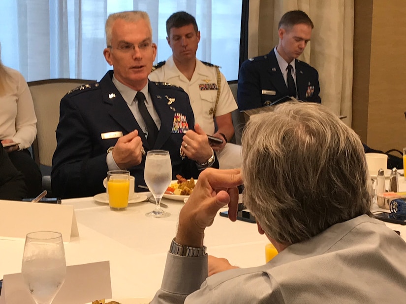 General sits at a table, talking to reporters.