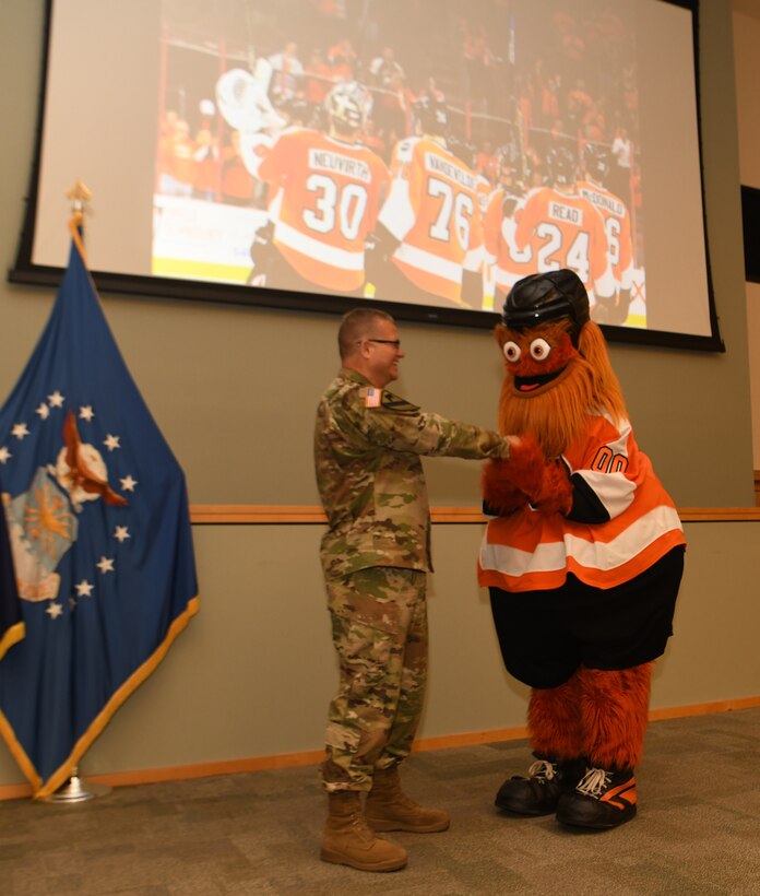 Defense Logistics Agency Troop Support commander Army Brig. Gen. Mark Simerly welcomes Gritty, the Philadelphia Flyers mascot, to Troop Support during a town hall in Philadelphia, June 11, 2019. Gritty’s surprise appearance symbolized the commander’s farewell message to the employees to “Stay Gritty.”  (Photo by Ed Maldonado/DLA Troop Support)