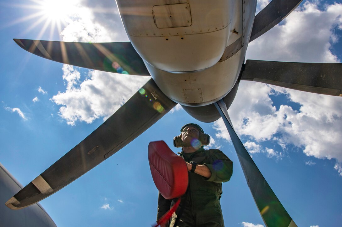 A Marine stands in front of a plane's propeller.