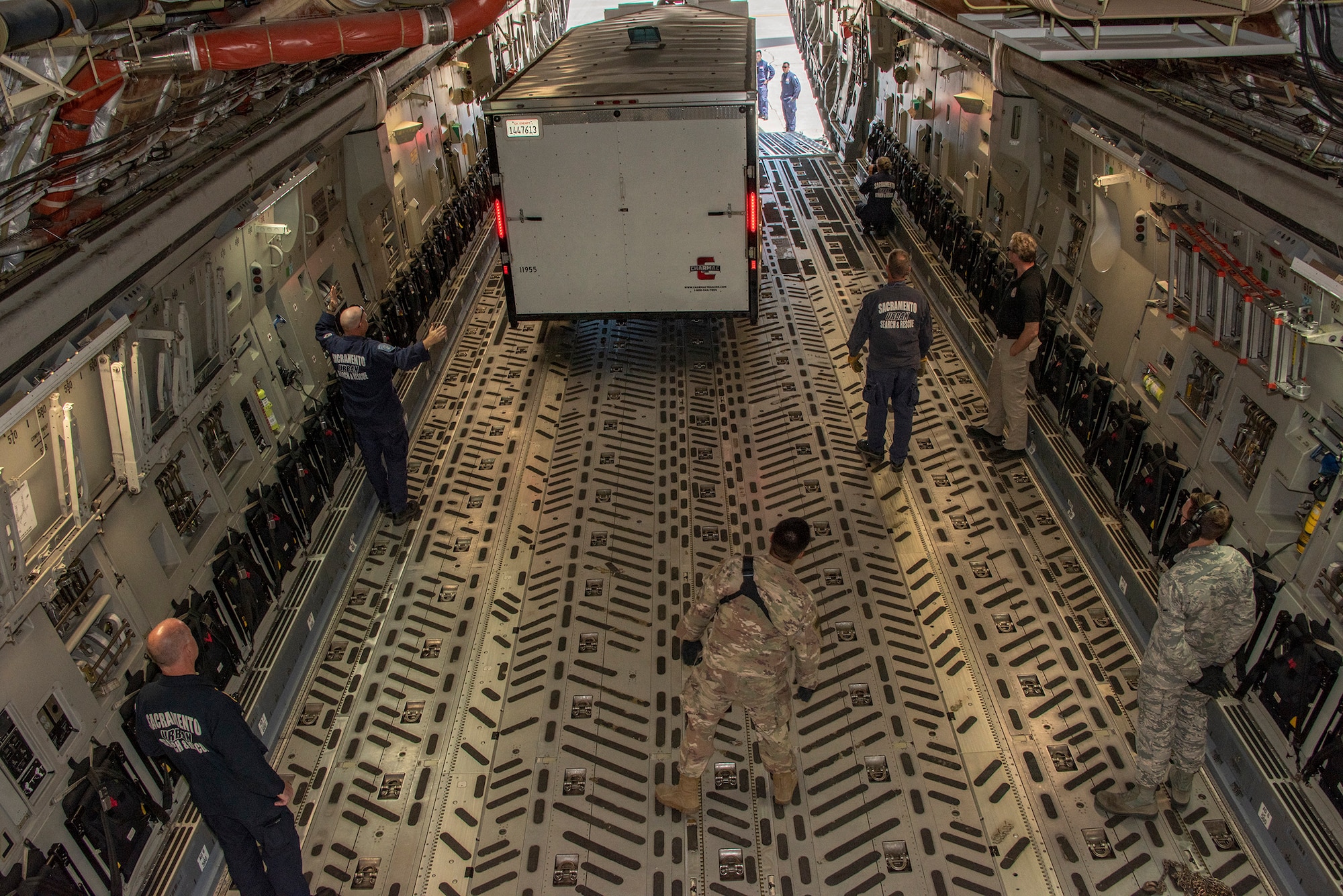 California Urban Search and Rescue Task Force 7 guides a cargo transport trailer into place inside a C-17 Globemaster III during a joint inspection and logistics drill conducted with 60th Aerial Port Squadron personnel, June 13, 2019 at Travis Air Force Base, California. The annual training helps members of CA TF-7 learn about the process, governing and directives and ensures cargo is safe before loading onto an aircraft.  (U.S. Air Force photo by Heide Couch)