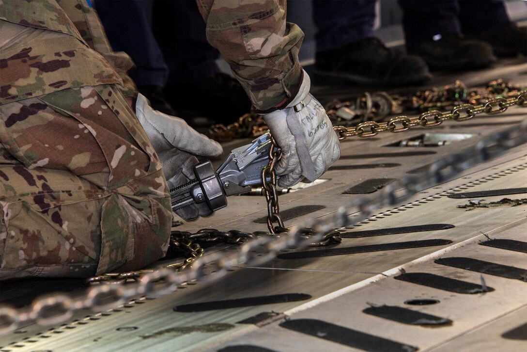 U.S. Air Force Senior Airman Edward Colvin, 60th Aerial Port Squadron expeditor, uses a chain to secure cargo to the deck of a C-17 Globemaster during a joint inspection and logistics drill conducted with California Urban Search and Rescue Task Force 7 June 13, 2019, at Travis Air Force Base, California. The annual training helps members of CA TF-7 learn about the process, governing and directives and ensures cargo is safe before loading onto an aircraft.  (U.S. Air Force photo by Heide Couch)