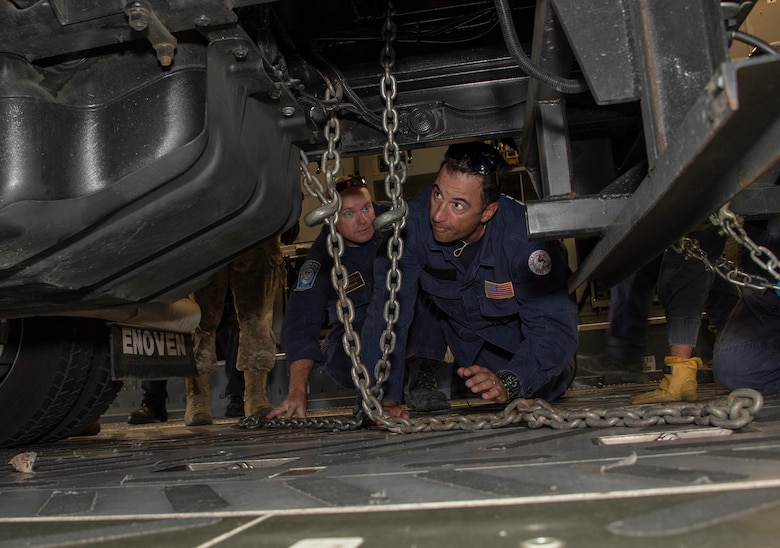 Liam McGregor, left, transportation manager and Matt Gonzales, California Urban Search and Rescue Task Force 7 transportation specialist, use a chain to secure an equipment transport trailer to the deck of a C-17 Globemaster III during a joint inspection and logistics drill conducted with 60th Aerial Port Squadron personnel June 13, 2019 at Travis Air Force Base, California. The annual training helps members of CA TF-7 learn about the process, governing and directives and ensures cargo is safe before loading onto an aircraft.  (U.S. Air Force photo by Heide Couch)