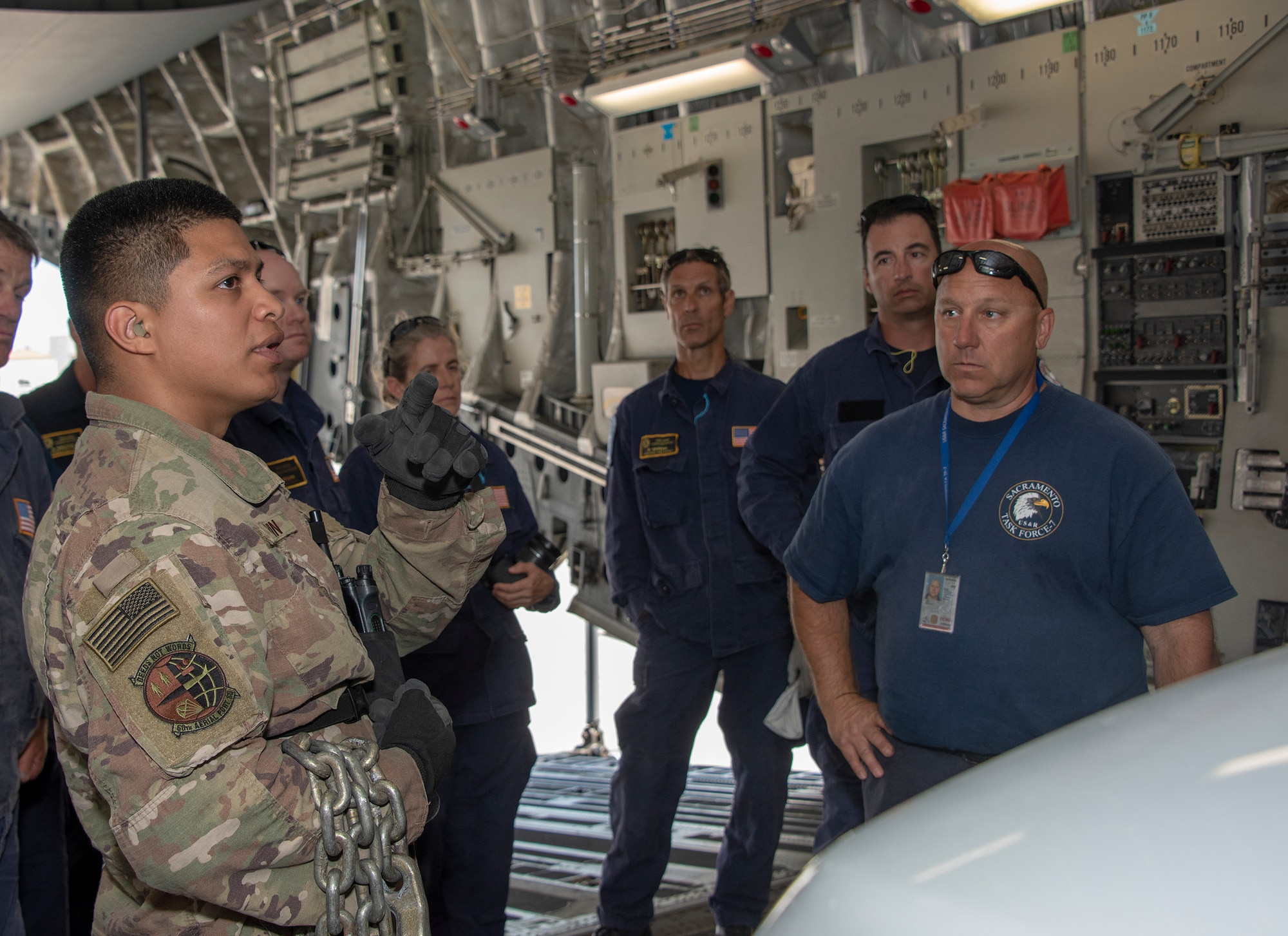 .S. Air Force Senior Airman Edward Colvin, left, a 60th Aerial Port Squadron expeditor, discuses cargo loading procedures with California Urban Search and Rescue Task Force 7 June 13, 2019 at Travis Air Force Base, California, during a joint inspection and logistics drill. The annual training helps members of CA TF-7 learn about the process, governing and directives and ensures cargo is safe before loading onto an aircraft.  (U.S. Air Force photo by Heide Couch)