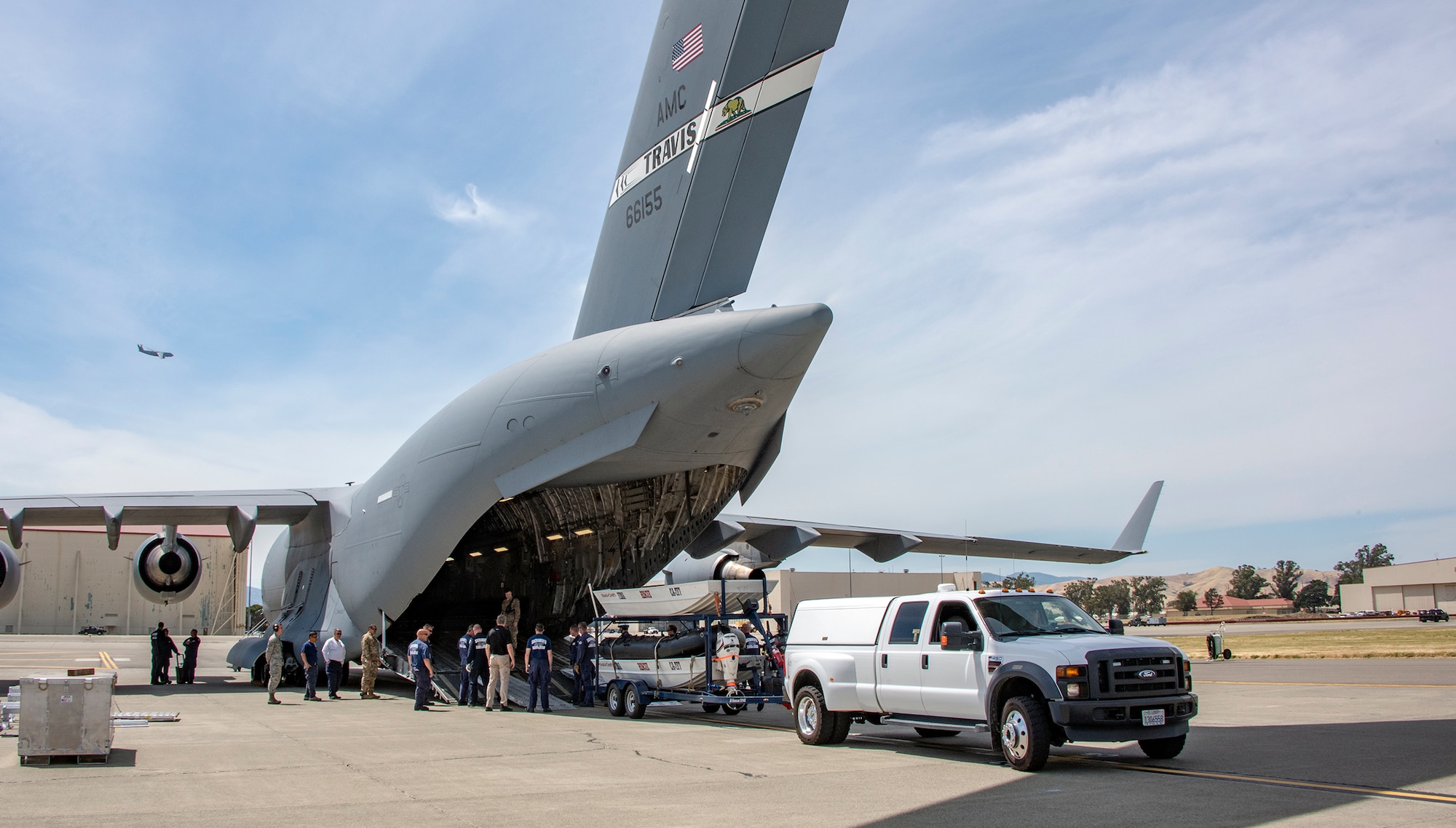 Members of California Urban Search and Rescue Task Force 7 and the 60th Aerial Port Squadron back a boat trailer into the cargo bay of a C-17 Globemaster III during a joint inspection and logistics drill June 13, 2019, at Travis Air Force Base, California. The annual training helps members of CA TF-7 learn about the process, governing and directives and ensures cargo is safe before loading onto an aircraft.  (U.S. Air Force photo by Heide Couch)
