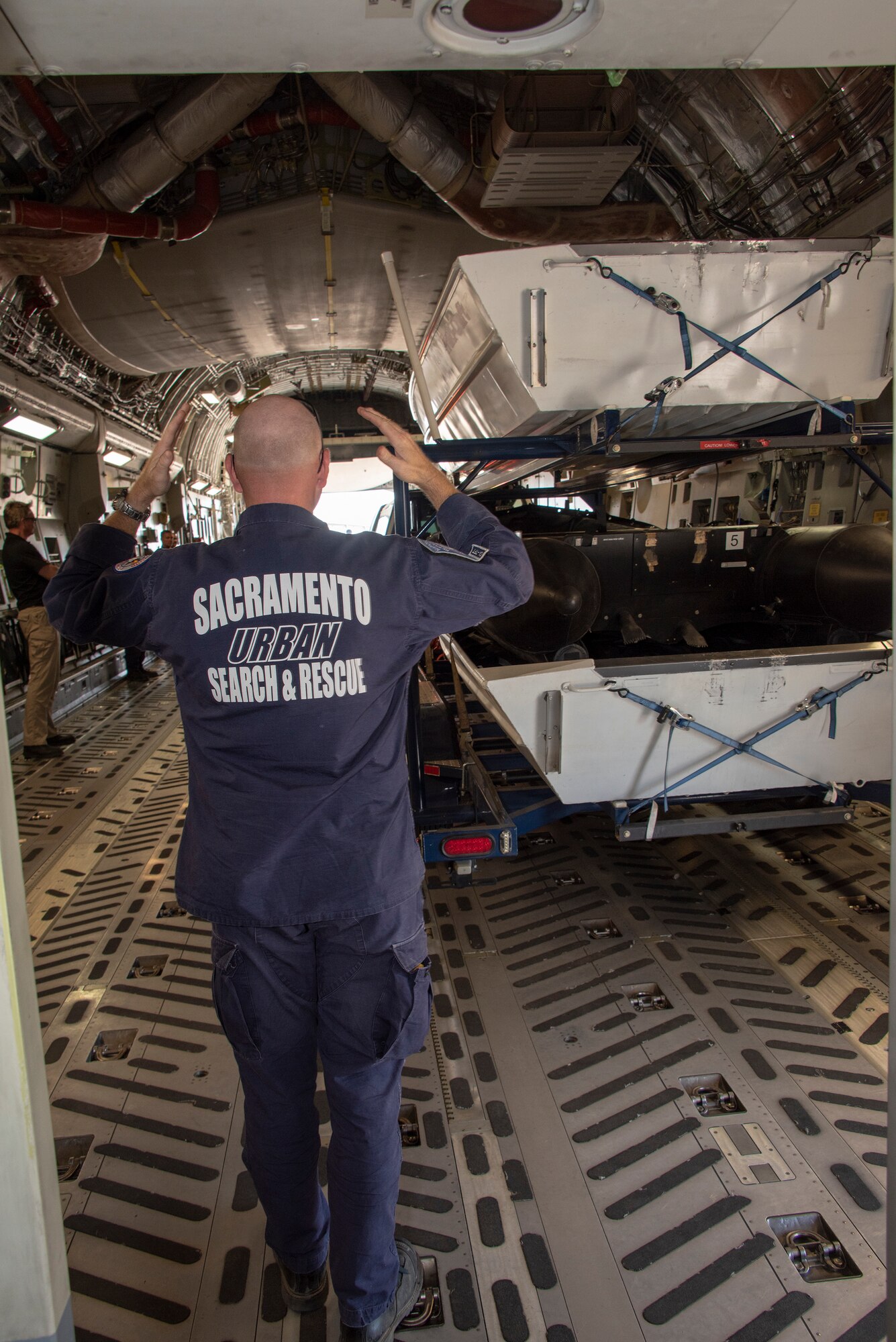 Members of California Urban Search and Rescue Task Force 7 and the 60th Aerial Port Squadron back a boat trailer into the cargo bay of a C-17 Globemaster III during a joint inspection and logistics drill June 13, 2019 at Travis Air Force Base, California. The annual training helps members of CA TF-7 learn about the process, governing and directives and ensures cargo is safe before loading onto an aircraft.  (U.S. Air Force photo by Heide Couch)