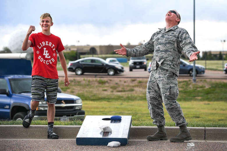 Colonel Brian Kehl, commander of the 50th Mission Support Group, and his son Mason play a game of corn hole during the monthly First Friday event on June 14, 2019 at Schriever Air Force Base, Colorado. Airmen and their families played games, ate free food and enjoyed performances of the 4th Infantry Division Band during the morale-building event.