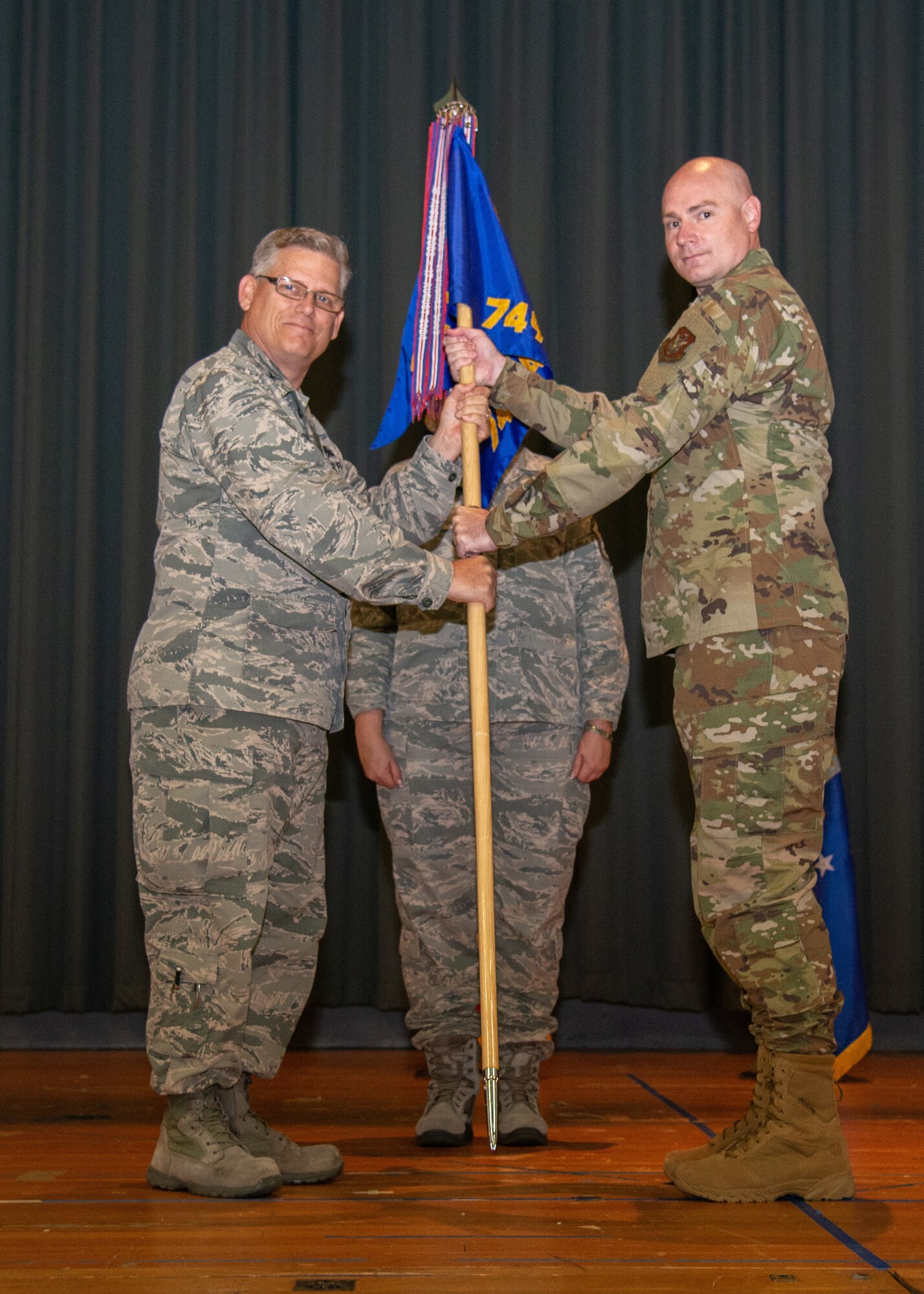 Col. Jeffrey Pickard, 349th Maintenance Group commander, hands the 749th Aircraft Maintenance Squadron guidon to Lt. Col. John Trueblood during a change of command ceremony June 2, 2019.