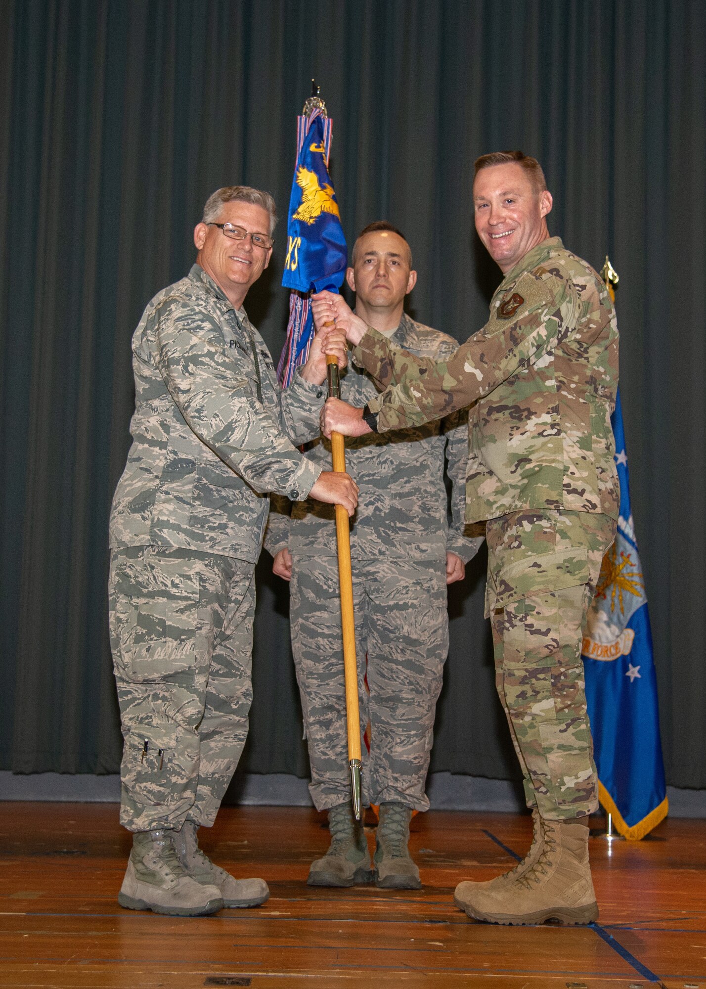 Col. Jeffrey Pickard, 349th Maintenance Group commander, hands the 349th Maintenance Squadron guidon to Maj. Daniel Noyer during an assumption of command ceremony June 2, 2019.