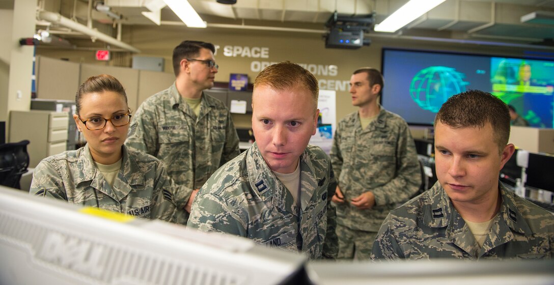 Airmen look at computer monitors.