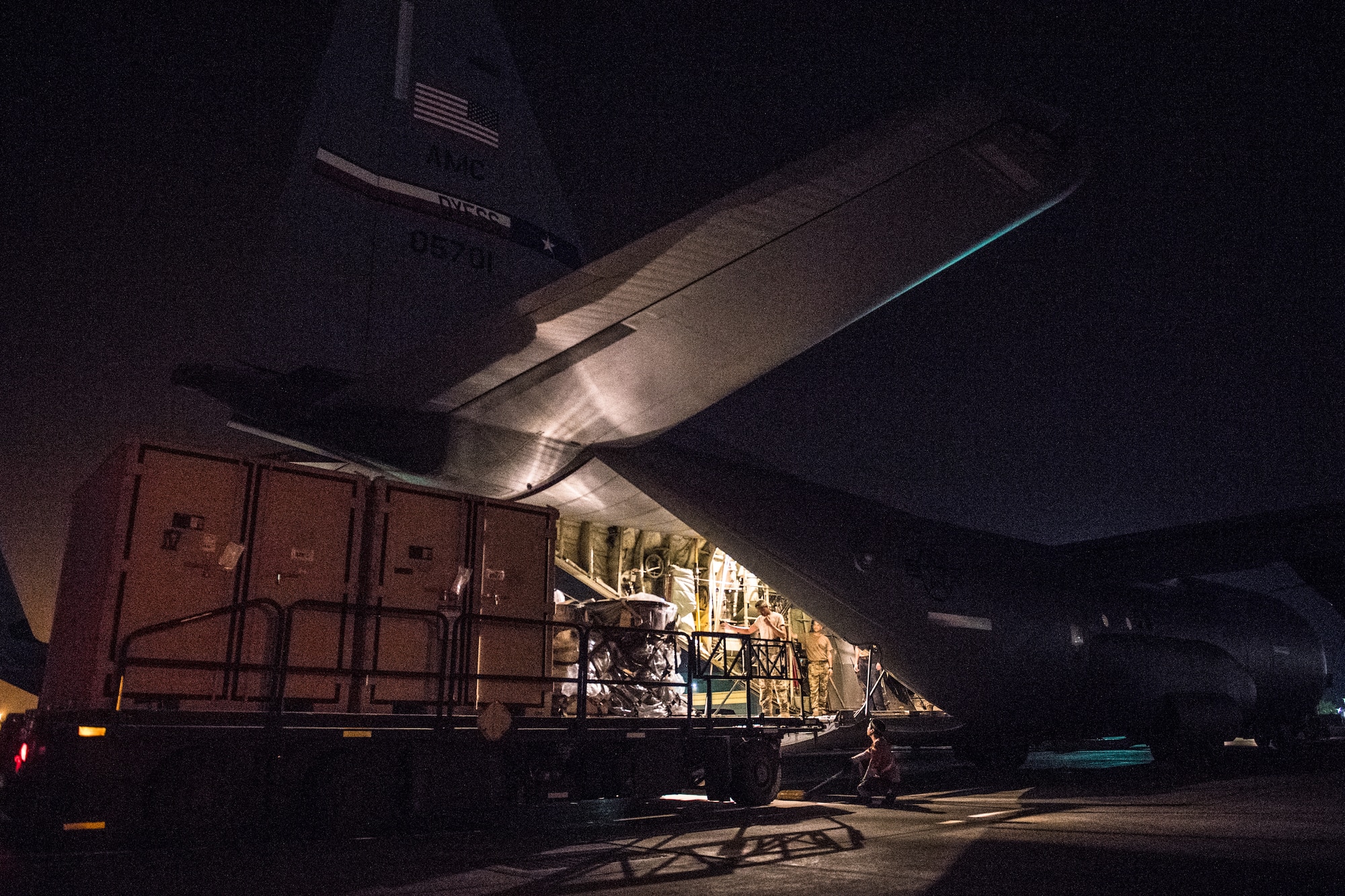 U.S. Air Force Airmen assigned to the 75th Expeditionary Airlift Squadron load two containers and luggage onto a C-130J Super Hercules at Camp Lemonnier, Djibouti, June 5, 2019. The 75th EAS provides support in medical evacuations, disaster relief, humanitarian and airdrop operations. (U.S. Air Force photo by Staff Sgt. Devin Boyer)
