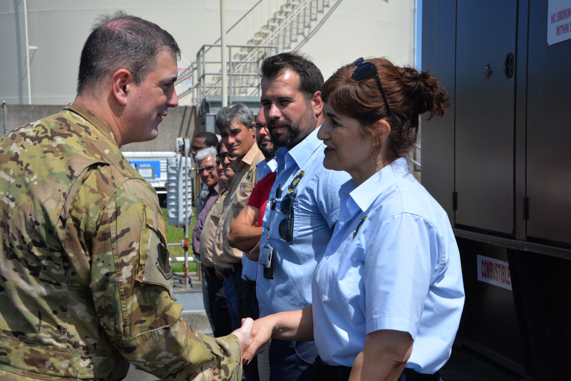 U.S. Air Force Brig. Gen. Mark R. August shakes hands with Mrs. Maria Costa as her teammate, Mr. Dinarco Coelho, looks on.  Both are 65th Logistics Readiness Squadron fuels distribution system workers who were named Airlifters of the Week 12 June for quickly reacting and putting out a fire at Lajes Field on May 23rd. (U.S. Air Force Photo by Rick Baptista)