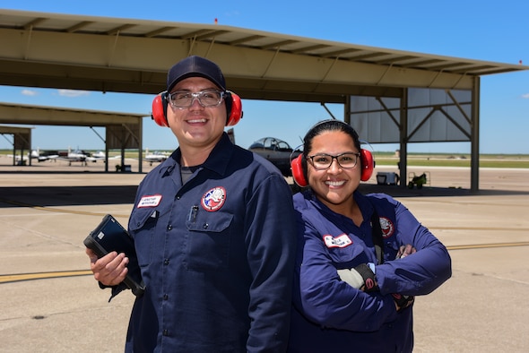 Jonathan and Michelle Merscham, 47th Maintenance Directorate aircraft attendants, pose on the flightline of Laughlin Air Force Base, Texas, on April 18, 2019. They go home smelling like fuel after feeling the fumes from the exhaust ripple in heat waves and the sun beating down. Even so, many maintainers are passionate about what they do, and have worked on the flightline for decades and plan to do so for decades to come. (U.S. Air Force photo by Senior Airman Anne McCready)