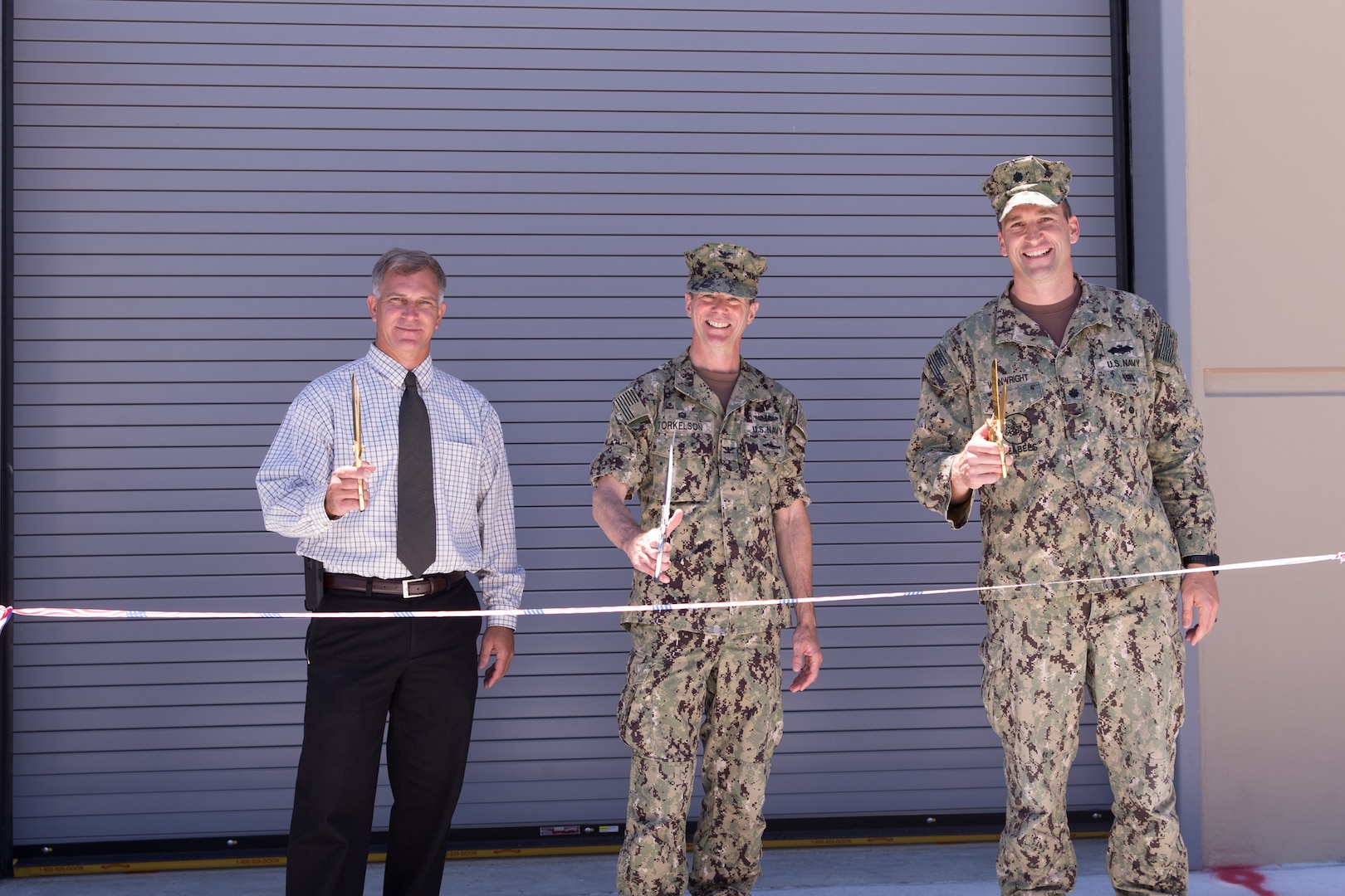 Norfolk Naval Shipyard dedicates its new Submarine Maintenance Facility June 14, consolidating submarine maintenance, production and support shops into a single facility adjacent to the shipyard's submarine drydocks and piers.  Participating in the ribbon-cutting from left to right are NNSY Submarine Program Manager Pat Ensley, Shipyard Commander Captain Kai Torkelson, and NAVFAC Public Works Officer Commander Ben Wainwright.
