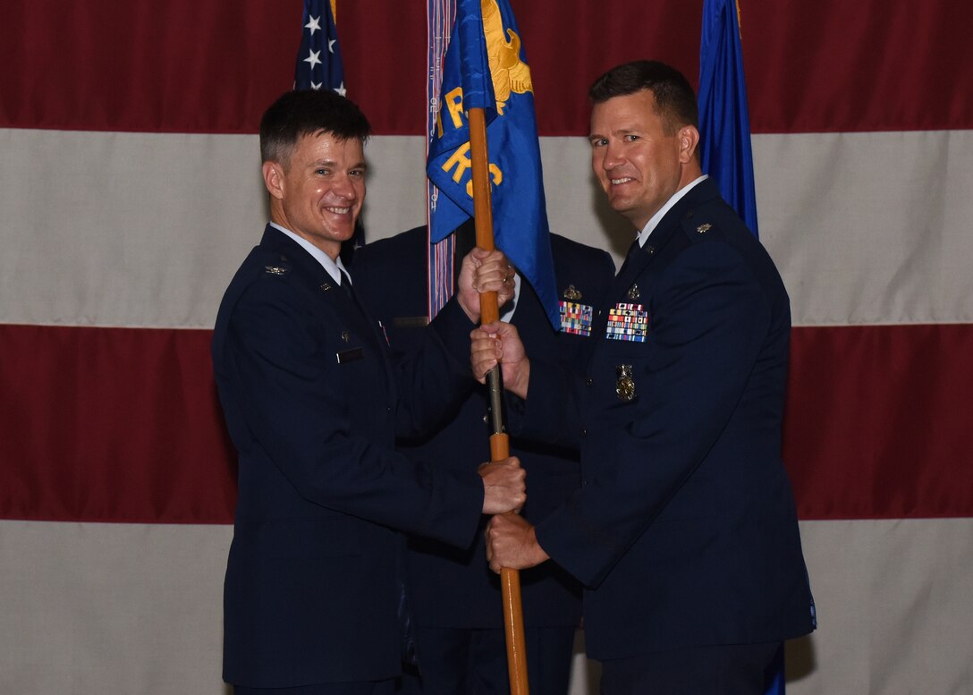 U.S. Air Force Col. Thomas Coakley, 17th Training Group commander, passes the guidon to Lt. Col. Michael McCourt, incoming 312th Training Squadron commander, during the change of command ceremony at the Louis F. Garland Department of Defense Fire Academy High Bay on Goodfellow Air Force Base, Texas, June 19, 2019. McCourt previously directed the senior team who created theater-wide posture strategies in support of the Info-Pacific Combatant Command. (U.S. Air Force photo by Airman 1st Class Zachary Chapman/Released)