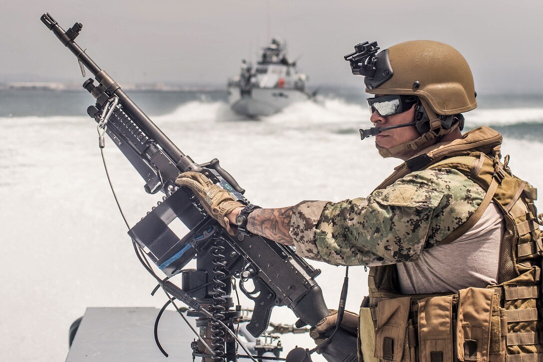 A sailor surveys an area while in a boat.