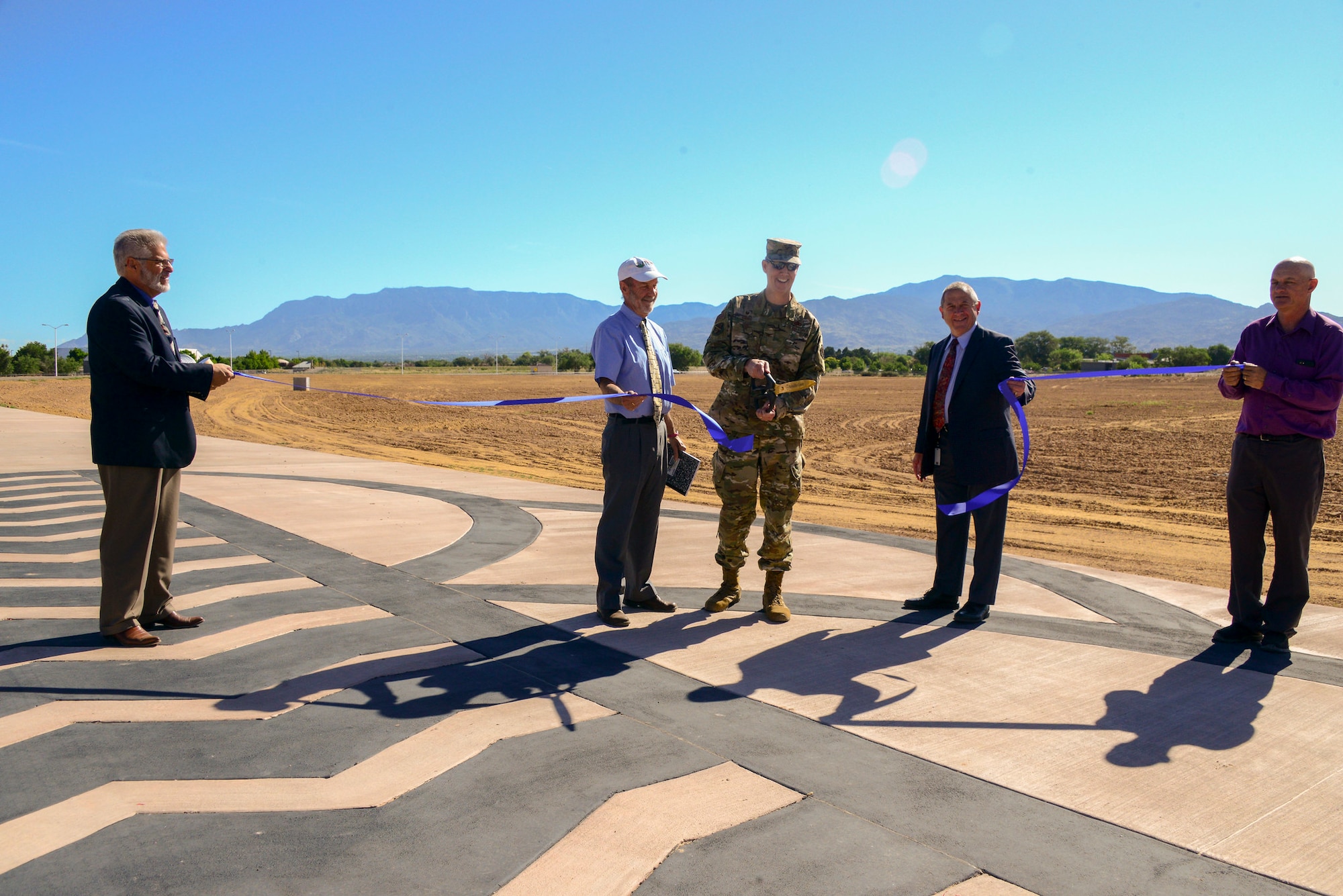 Col. Richard Gibbs, Mr. Jerry Lovato and other city and Albuquerque Metropolitan Arroyo Flood Control Authority members cut a ribbon at an official ceremony recognizing the Louisiana Gibson Regional Drainage Facility completion at Kirtland June 19, 2019. AMAFCA completed the project that was jointly funded by the Air Force, AMAFCA and the City of Albuquerque. The $2,520,000 project was designed for two major functions: a regional storm water detention facility and a realignment to the Gibson Gate. (U.S. Air Force photo by Jessie Perkins)