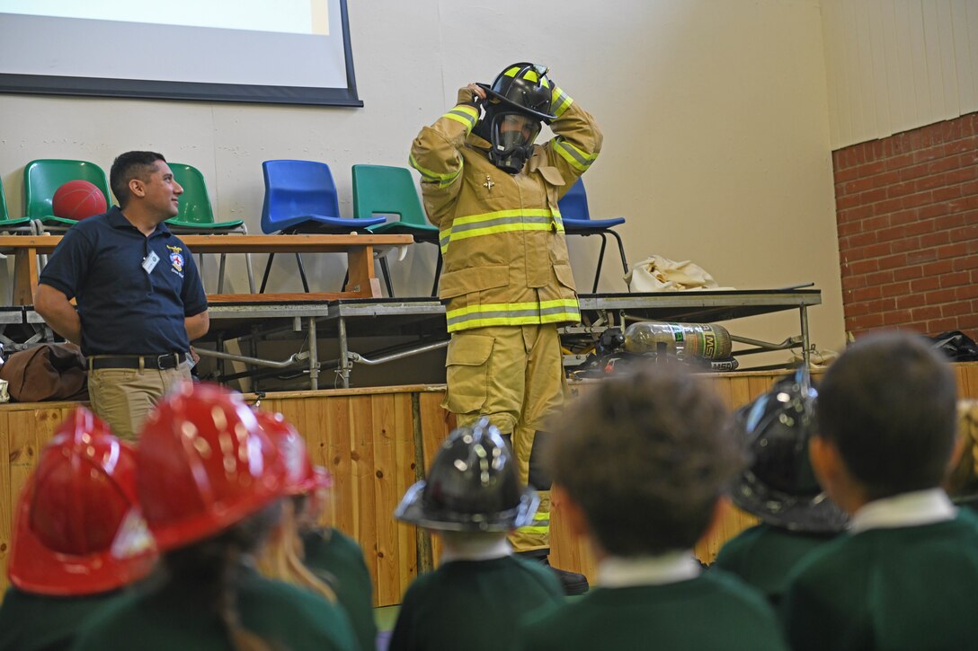 U.S. Air Force Senior Airman Alek Rodriguez, 100th Civil Engineer Squadron firefighter, dons his firefighting equipment during a demonstration for students at Great Heath Academy, Mildenhall, England, June 19, 2019.  Volunteers from the 100th CES fire department came to the school to teach fire safety and show the students firefighting equipment. (U.S. Air Force photo by Senior Airman Luke Milano)
