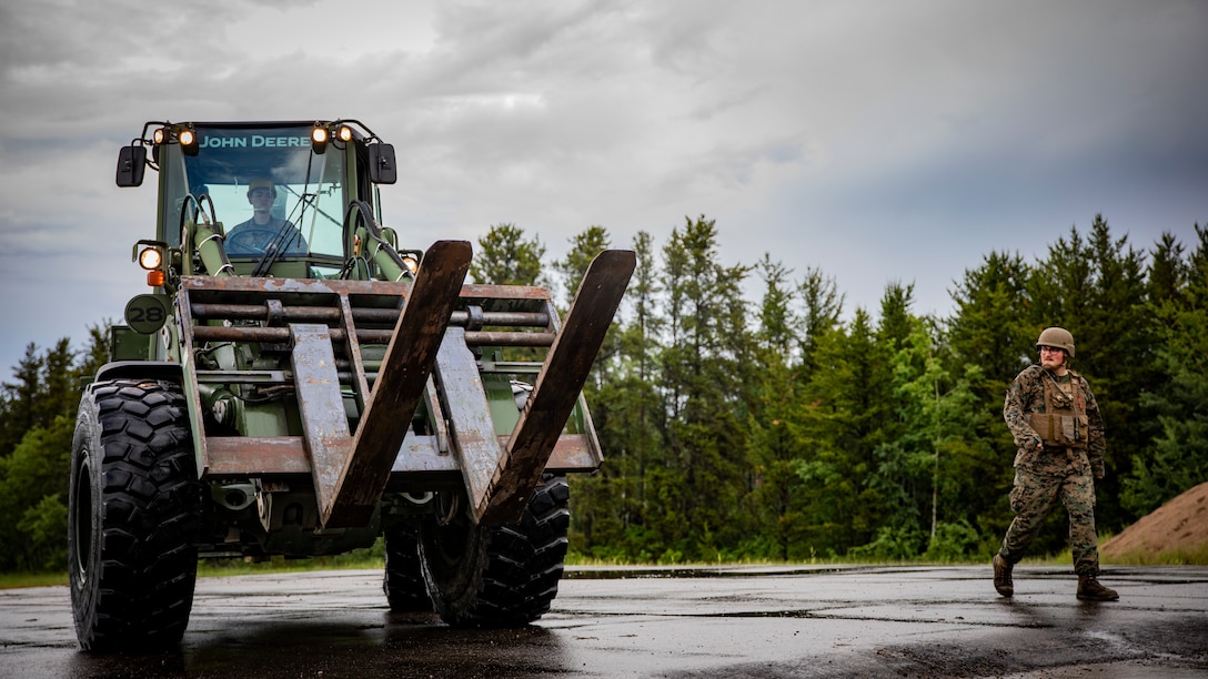 U.S. Marine Corps Cpl. Ryan Donnelly, left, a heavy equipment operator with Marine Wing Support Squadron 471, Marine Aircraft Group 41, 4th Marine Aircraft Wing, operates a tractor at Canadian Forces Base Cold Lake, Canada, June 19, 2019, in support of Sentinel Edge 19. Training exercises, such as SE19, ensure Reserve Marines are proficient and capable of successful integration with active-duty Marines, making MARFORRES critical to the Marine Corps’ Total Force. (U.S. Marine Corps photo by Lance Cpl. Jose Gonzalez)