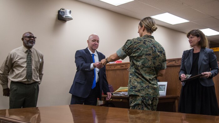Lt. Col. Kara J. Zummo, officer in charge, Legal Service Support Team, Headquarters Battalion, Marine Corps Air Ground Combat Center (MCAGCC), presents coins to the members of San Bernardino County Child Support Services after a certificate of appreciation presentation at MCAGCC, Twentynine Palms, Calif., June 18, 2019. The section was awarded a certificate of appreciation for their work with the San Bernardino County Child Support Services. (U.S. Marine Corps photo by Cpl. Francisco J. Britoramirez)