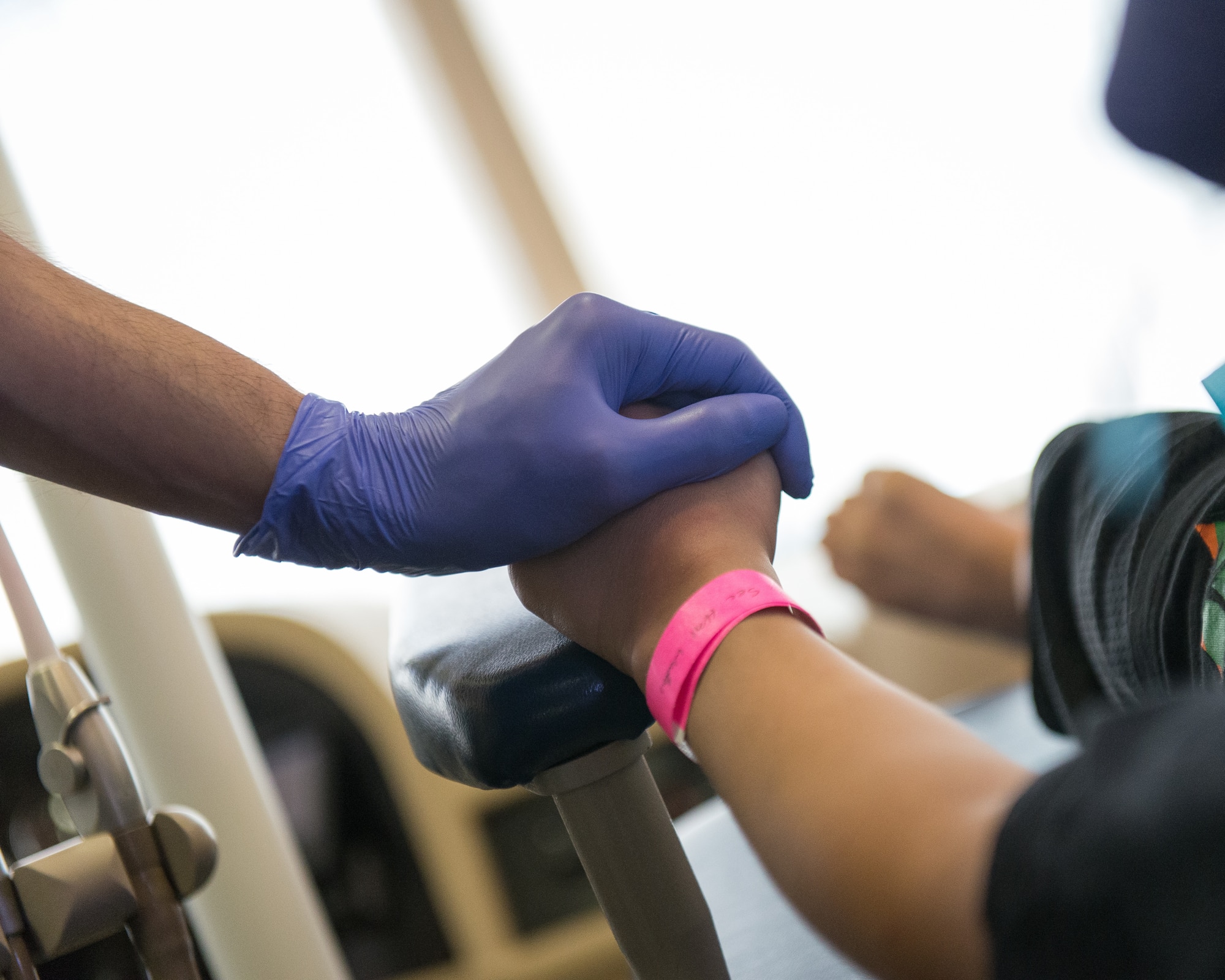 U.S. Air Force Tech Sgt. Eddie Perez, a dental technician assigned to the 176th Wing, Alaska Air National Guard, holds a child's hand during a tooth extraction procedure at a temporary clinic in Sikeston, Mo., June 19, 2019. U.S. service members deployed to Sikeston as part of a joint service medical exercise that provides training to service members and no-cost medical services to the community. (U.S. Air National Guard photo by Senior Airman Jonathan W. Padish)