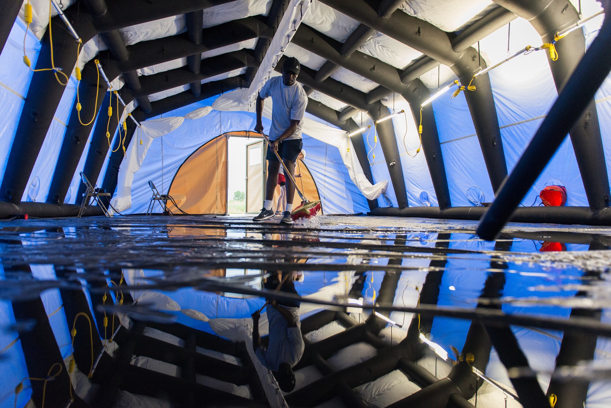 A biomedical equipment technician removes water from a flooded inflatable air shelter