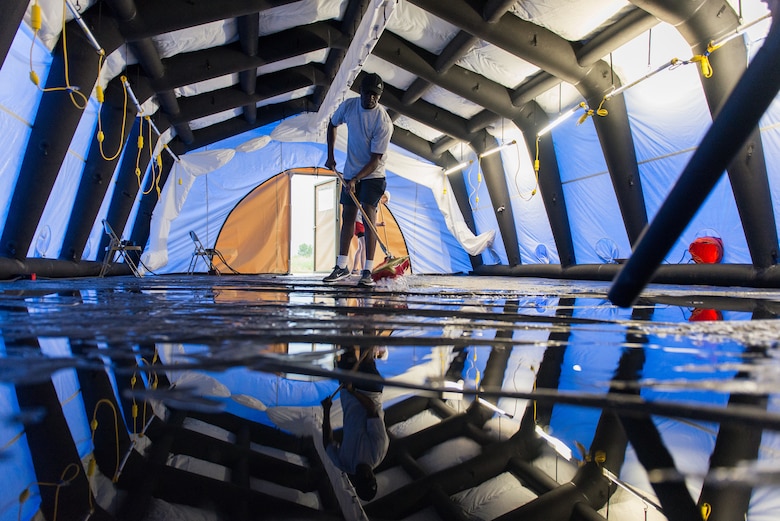 A biomedical equipment technician removes water from a flooded inflatable air shelter