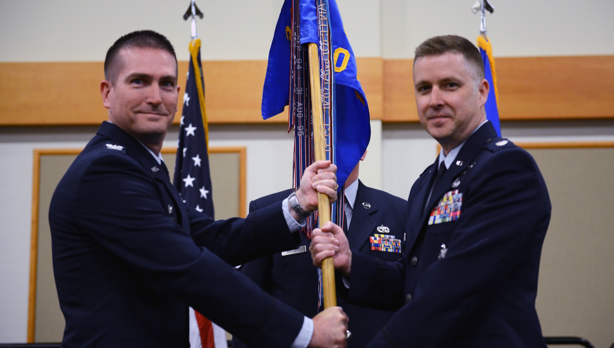 Lt. Col. Jeffrey Regan, right, accepts command of the 10th Missile Squadron from Col. Christopher Menuey, 341st Operations Group commander, during a change of command ceremony June 20, 2019, at the Grizzly Bend on Malmstrom Air Force Base, Mont. Guidon bearer Master Sgt. Brook Mertens, 10th MS facility manager, looks on. (U.S. Air Force photo by Staff Sgt. Magen M. Reeves)