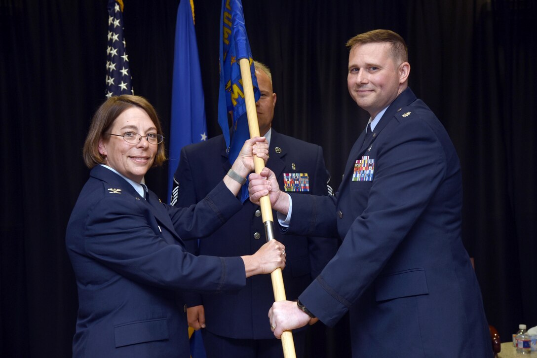 72nd Medical Group Commander Col. Jennifer Trinkle presents the guidon of the 72nd Medical Operations Squadron to the new commander, Lt. Col. Colin Burchfield during a formal change of command ceremony June 13. Lt. Col. Randall Stevens relinquished command of the squadron he led for the past two years. (U.S. Air Force photo/Kelly White)
